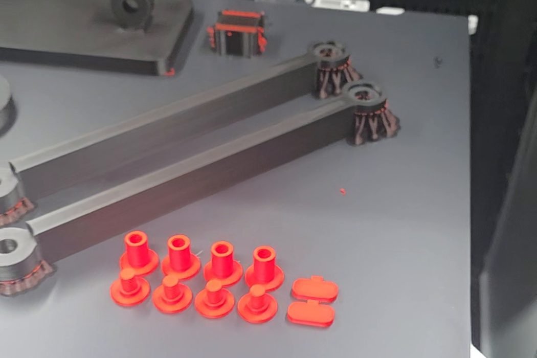 Piese roșii printate 3D pe placa imprimantei, în atelierul Sanel Factory